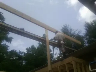 Carpenter setting a ridge beam over a new addition frame — Ice Dam Removal by Roofing Brothers in Loma