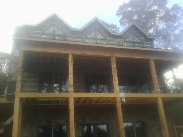 Dormers and porch framing on a large log home under construction — Roof Coating work by our crew in Loma