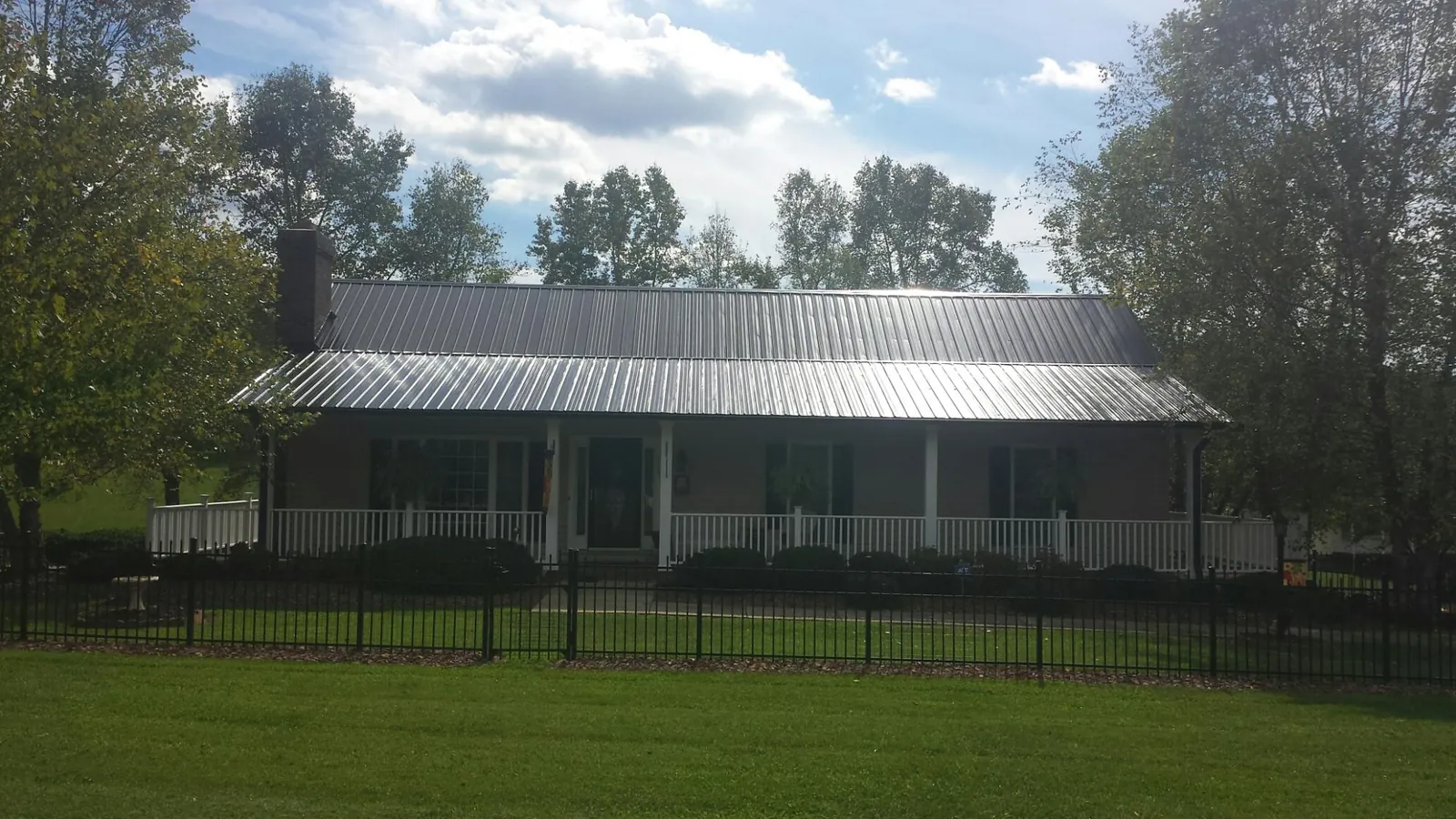 Gray metal roof on a brick ranch with a full width front porch — Gutter Guard Installation work by our crew in Loma