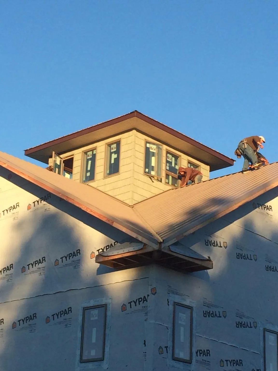 Roofers working around a rooftop cupola on a new metal roof at sunset — Roof Waterproofing in Loma by Roofing Brothers
